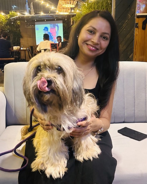 Smiling with a fluffy dog on a cafe sofa
